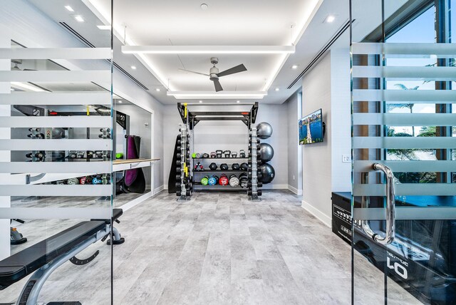 exercise room featuring a raised ceiling, ceiling fan, and carpet floors