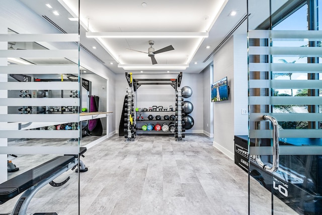 workout area featuring recessed lighting, a raised ceiling, baseboards, and wood finished floors