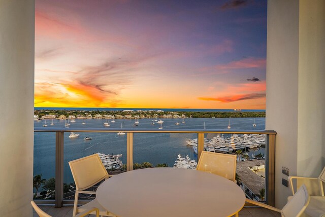 balcony at dusk featuring a water view