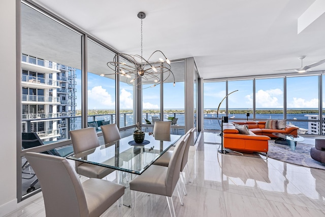 dining room with ceiling fan with notable chandelier, a water view, and floor to ceiling windows