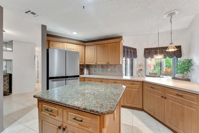 kitchen with tasteful backsplash, an inviting chandelier, stainless steel refrigerator, and light tile patterned floors