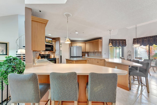 kitchen featuring light brown cabinetry, decorative backsplash, black appliances, and kitchen peninsula