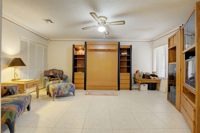 sitting room featuring a textured ceiling, light tile patterned floors, ceiling fan, and crown molding