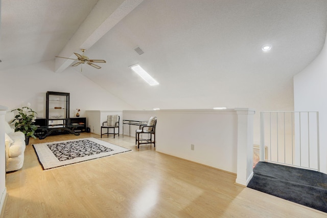 sitting room with light wood-type flooring, ceiling fan, and vaulted ceiling with beams