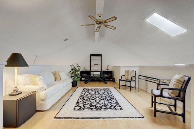 living room with light hardwood / wood-style flooring, ceiling fan, and lofted ceiling with skylight