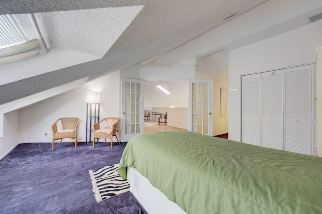 carpeted bedroom featuring french doors, a textured ceiling, and a closet