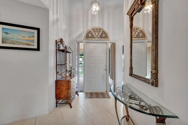 tiled entrance foyer featuring a high ceiling and a notable chandelier