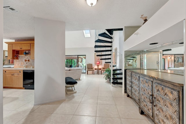 corridor featuring a textured ceiling, light tile patterned floors, and a skylight