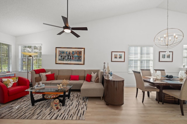 living room with ceiling fan with notable chandelier, a textured ceiling, light wood-type flooring, and vaulted ceiling