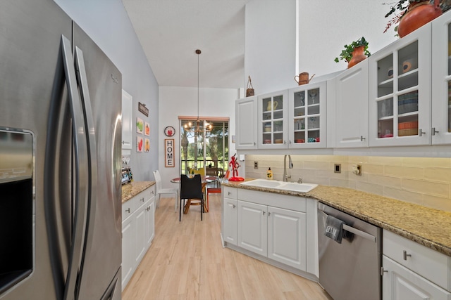 kitchen featuring appliances with stainless steel finishes, light wood-type flooring, sink, white cabinetry, and lofted ceiling