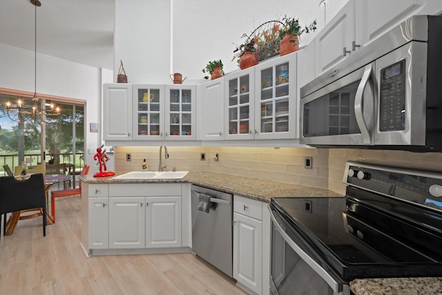 kitchen featuring stainless steel appliances, sink, a notable chandelier, light hardwood / wood-style floors, and white cabinetry