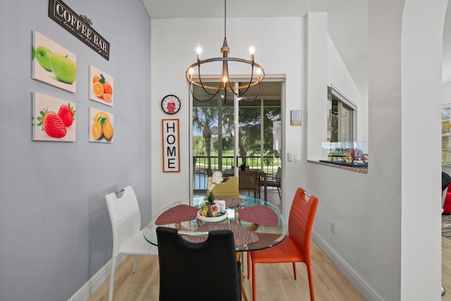 dining space with a wealth of natural light, light hardwood / wood-style floors, and an inviting chandelier