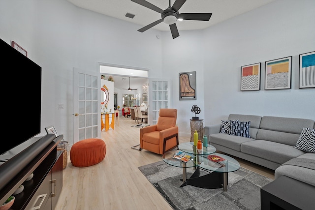 living room with ceiling fan, french doors, high vaulted ceiling, and light hardwood / wood-style floors