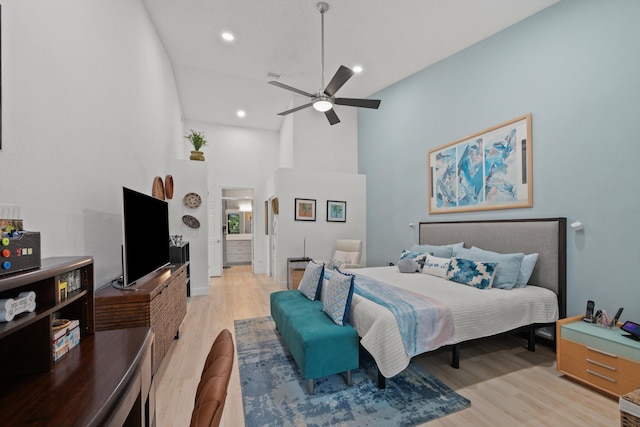 bedroom with a high ceiling, light wood-type flooring, and ceiling fan