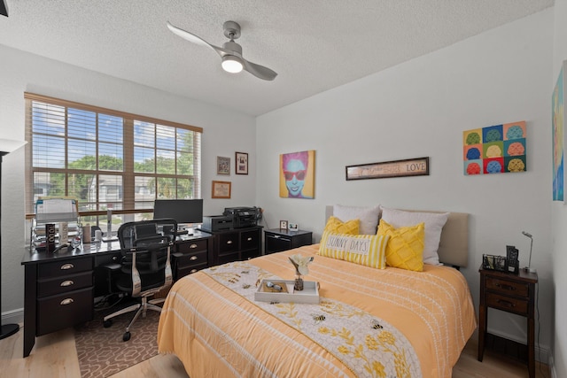 bedroom with a textured ceiling, light wood-type flooring, and ceiling fan