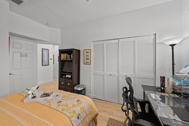 bedroom featuring a textured ceiling, light wood-type flooring, and a closet