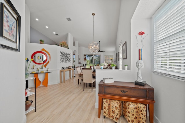 dining space featuring high vaulted ceiling, light wood-type flooring, and an inviting chandelier