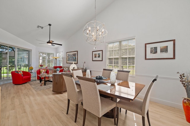 dining room featuring ceiling fan with notable chandelier, light hardwood / wood-style floors, and high vaulted ceiling