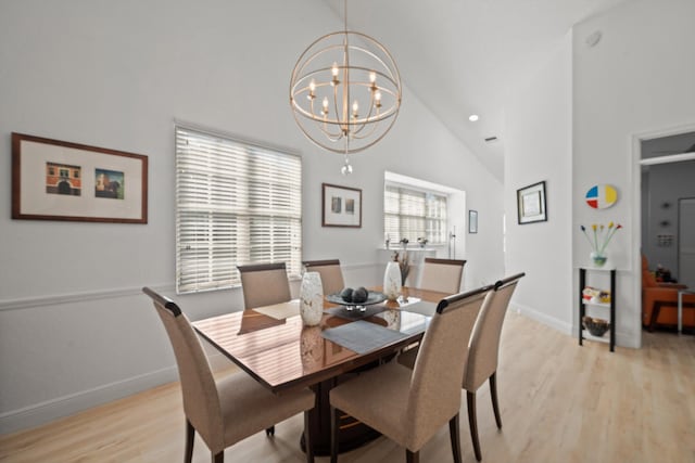 dining area with light hardwood / wood-style flooring, high vaulted ceiling, and a chandelier