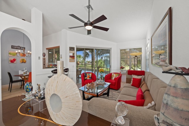 living room with vaulted ceiling, ceiling fan with notable chandelier, and hardwood / wood-style floors