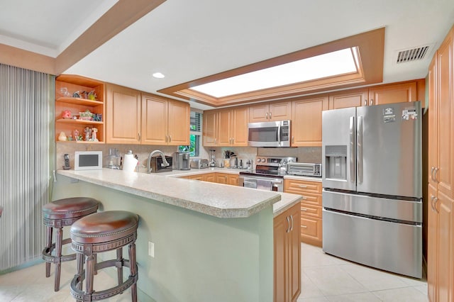 kitchen featuring kitchen peninsula, stainless steel appliances, light tile patterned floors, and a breakfast bar