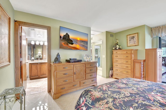 bedroom with ensuite bathroom, light tile patterned floors, and sink