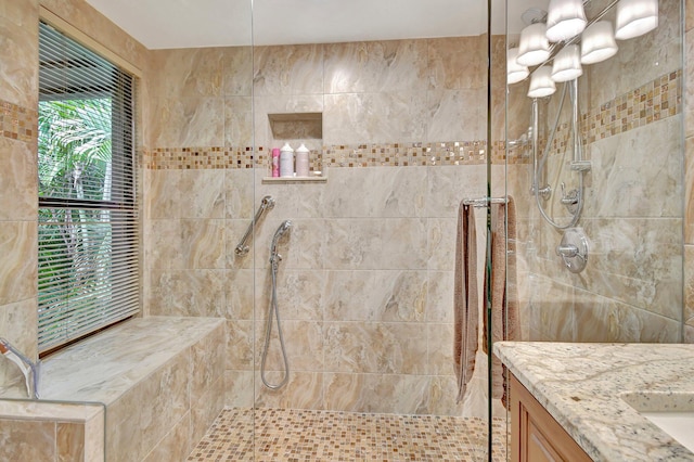 bathroom featuring tiled shower and vanity