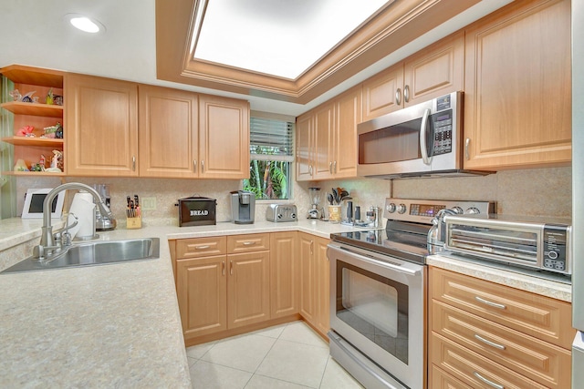 kitchen featuring sink, ornamental molding, light tile patterned flooring, a raised ceiling, and appliances with stainless steel finishes