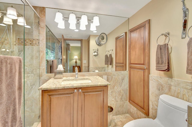 bathroom featuring tile walls, toilet, vanity, and a tile shower