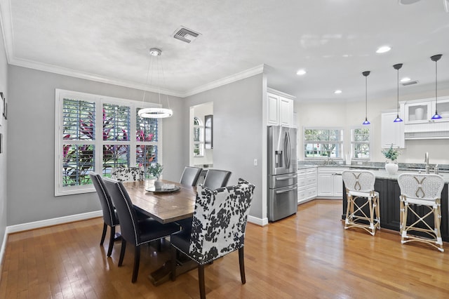 dining room with sink, light hardwood / wood-style flooring, and crown molding