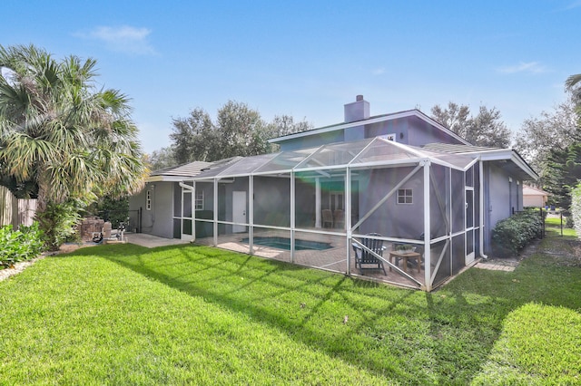 back of property featuring glass enclosure, a yard, and a patio area