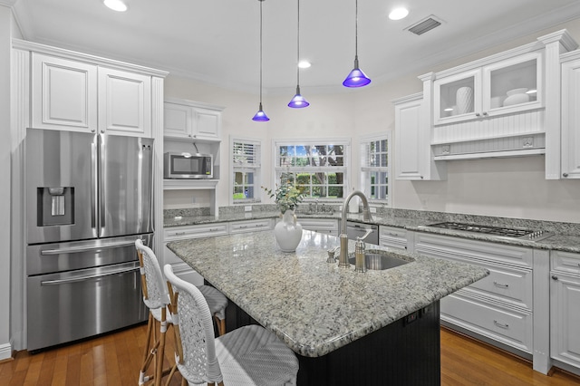 kitchen featuring white cabinets, stainless steel appliances, dark wood-type flooring, and an island with sink