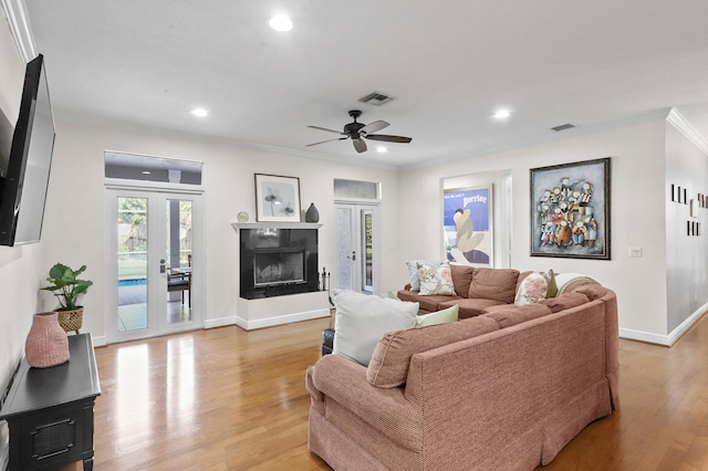 living room with ceiling fan, french doors, ornamental molding, and light hardwood / wood-style flooring