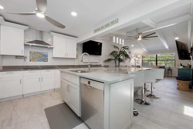 kitchen featuring dishwasher, a kitchen island with sink, white cabinets, wall chimney range hood, and a kitchen bar