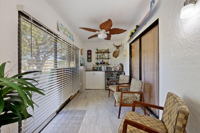 living area featuring indoor bar and ceiling fan