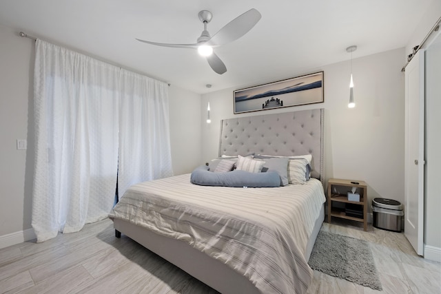 bedroom with a barn door, ceiling fan, and a closet