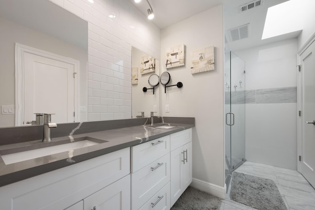 bathroom featuring vanity, a shower with door, and a skylight