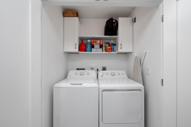 laundry area with washer and clothes dryer, cabinets, and a textured ceiling