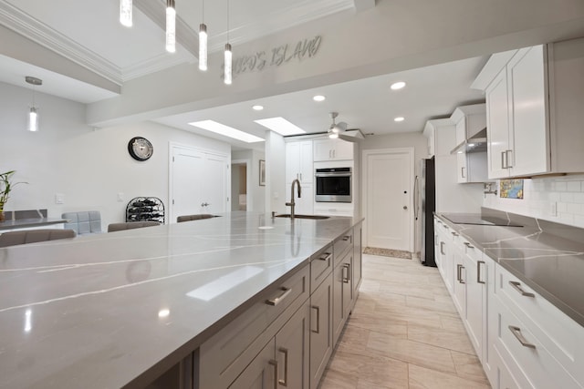 kitchen with sink, stainless steel appliances, light stone counters, pendant lighting, and white cabinets