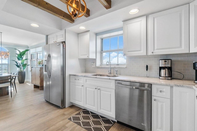 kitchen featuring stainless steel appliances, hanging light fixtures, white cabinets, beamed ceiling, and light hardwood / wood-style flooring