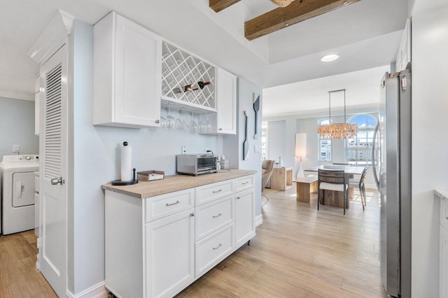 kitchen with pendant lighting, stainless steel fridge, light wood-type flooring, and washer / clothes dryer