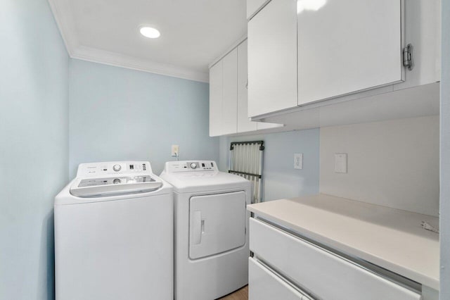 clothes washing area featuring ornamental molding, cabinets, and washer and dryer