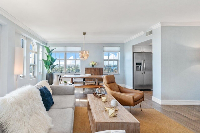 living room with an inviting chandelier, hardwood / wood-style flooring, and ornamental molding