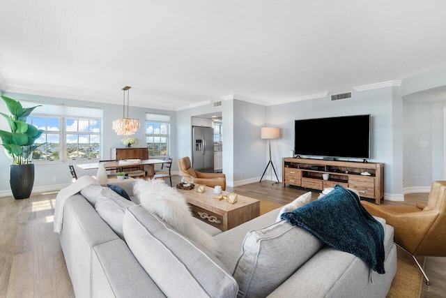 living room with light wood-type flooring, a chandelier, and crown molding