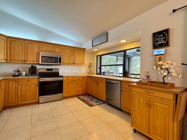 kitchen with lofted ceiling, sink, light tile patterned floors, and stainless steel appliances