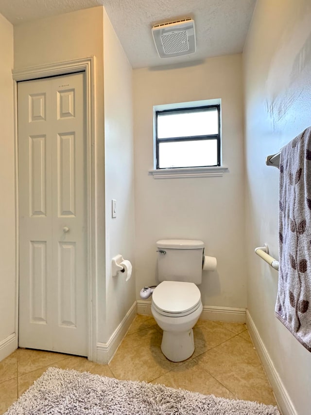 bathroom featuring tile patterned floors, a textured ceiling, and toilet