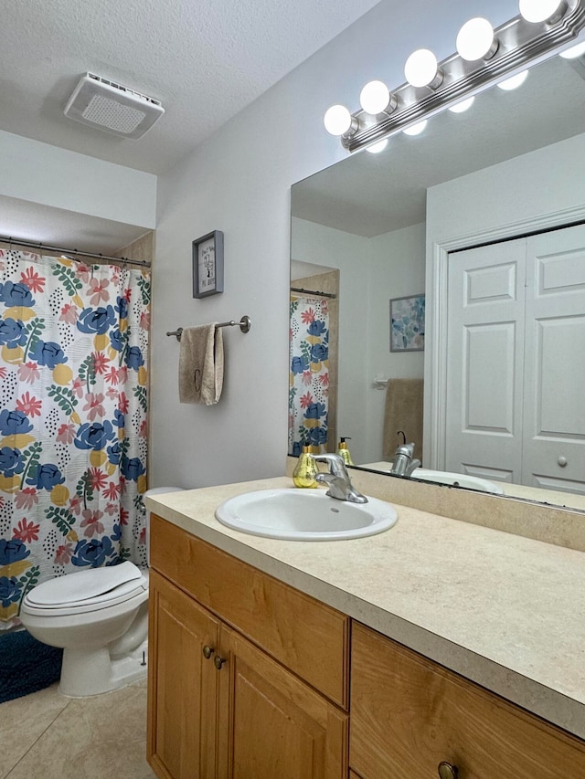 bathroom with tile patterned flooring, vanity, a textured ceiling, and toilet