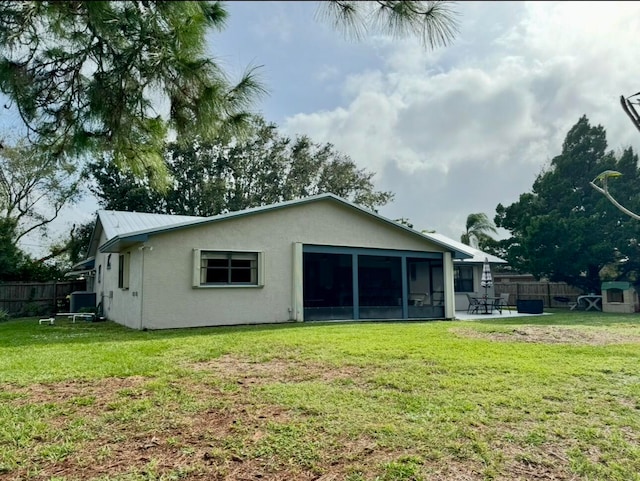 back of property with a lawn and a sunroom