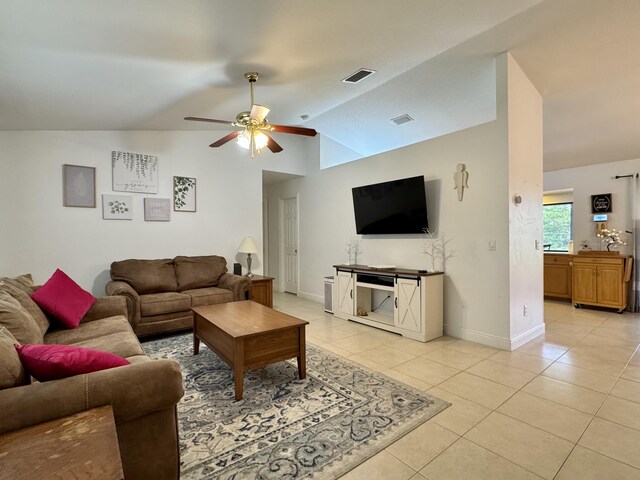 tiled living room featuring ceiling fan with notable chandelier and vaulted ceiling