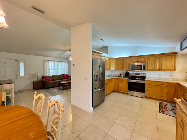 kitchen with ceiling fan, light tile patterned floors, appliances with stainless steel finishes, and vaulted ceiling